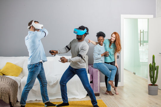 Group of multiracial male amd female students playing virtual game using vr goggles, having fun together ay home - Virtual omg reality and portable digital technologies