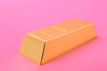 Precious shiny gold bar on color background