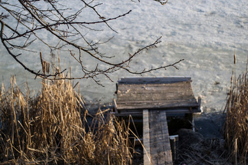 Old wooden bridge in the frozen pond.