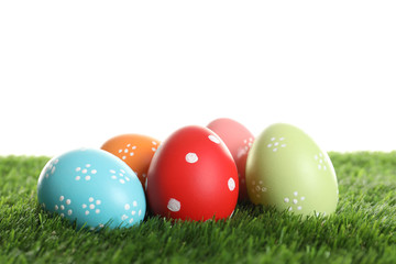 Colorful painted Easter eggs on green grass against white background