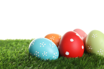 Fototapeta na wymiar Colorful painted Easter eggs on green grass against white background