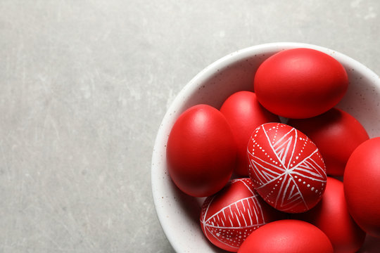 Bowl with red painted Easter eggs on table, above view. Space for text