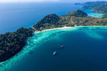 Aerial drone view of a beautiful tropical island surrounded by coral reefs and covered with lush, green jungle (Kyun Phi Lar, Myanmar)