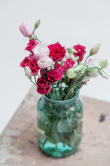 Bouquet of red Eustoma in glass jar on white background