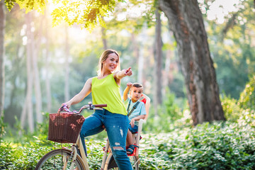 Family on bikes- mother and son riding a bicycle together in park.