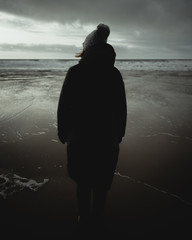 silhouette of a woman in winter looking to sea