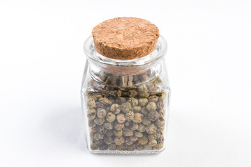 green pepper peppercorns  in a glass jar isolated on white background