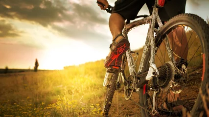 Plexiglas foto achterwand Cyclist riding bike down hill at sunset © Leart