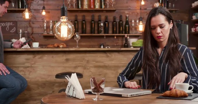Stylish young woman asking the bartender for the bill and making the payment. Using her smartphone to make a payment after a luch break.