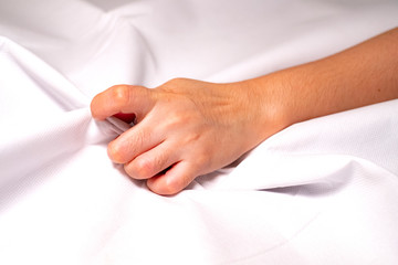 Woman hand squeezing bed sheets color white