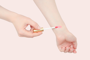 Caucasian girl makes sweat lip gloss on hand. View from above. Pink background.