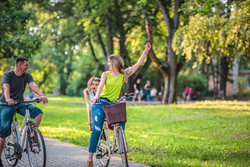 Happy father and mother with kid on bicycles having fun in park..