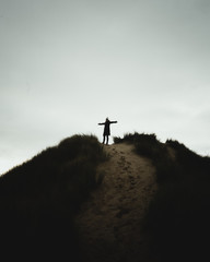 silhouette of woman on top of sand dune