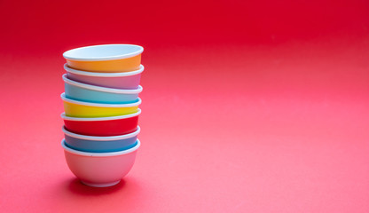 Colorful clean ceramic bowls stacked on red color background, copy space