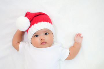 Asian newborn baby wear white dress and red Christmas knitting hat on white towel background. Newborn baby is ready for Christmas.