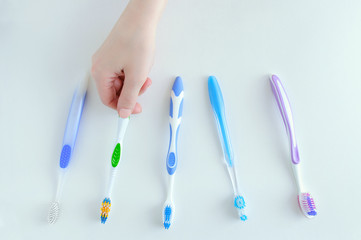 Caucasian girl chooses a toothbrush. View from above. White background.