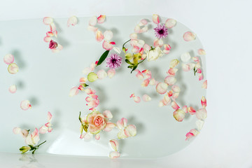Top view of bath filled with bubble water, flowers and petals, spa or selfcare concept