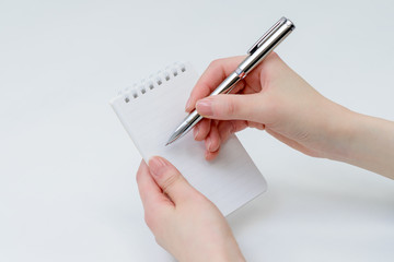 メモ帳にペンで何か書いているところ