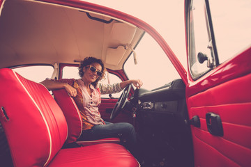 Beautiful alternative hippy style caucasian woman sit down inside her old retro restored red car...