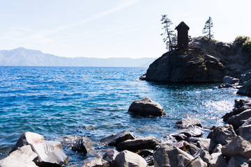 View of cliffs surrounding Crater Lake, blue water and rocky shoreline