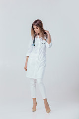 Full length portrait of medical physician doctor woman in white coat with stethoscope on light background.