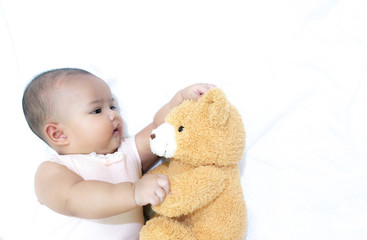 Asian baby hug her brown bear doll on white background. Baby girl loves her bear doll friend.