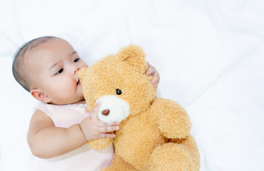 Asian baby hug her brown bear doll on white background. Baby girl loves her bear doll friend.
