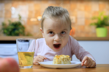 Funny little girl eating apple pie at home
