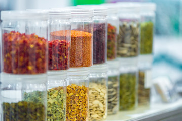 Dried vegetables in glass jars, onions, beets, carrots, pumpkin, bay leaf, banks on blurred background. Superfoods, herbs.