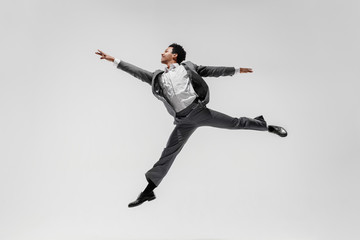 Happy businessman dancing in motion isolated on white studio background. Flexibility and grace in...