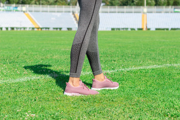 Woman with pink sneakers standing on football field with the white line. ready for running on the stadium