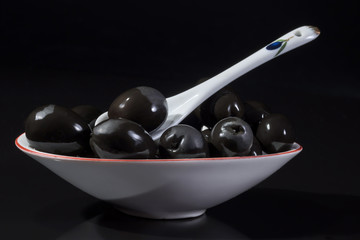 Plateful of black olives on a black background