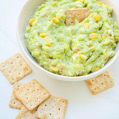 Bowl of guacamole with crackers. Fresh guac with avocado based dip, traditional mexican dish. Simple to make at home with a few natural ingredients. Party food. Healthy snack.