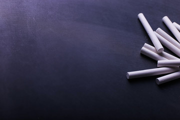 Crayons lie on a black chalkboard, copy space. The concept of school, education and childhood.