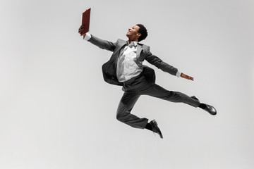 Happy businessman dancing in motion isolated on white studio background. Flexibility and grace in...