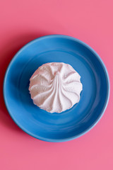 Marshmallow in a blue plate on a pink background. vertical photo.