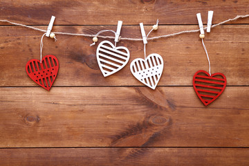 Valentines day romantic background, red and white handmade wood toy decorative hearts hanging on brown wooden table, happy holiday on February 14, dating and love concept, top view, copy free space