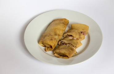 Two fried pancakes with ham and cheese filling on a white plate, white, gray background