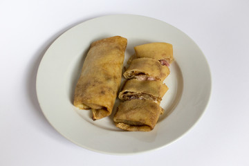 Bad photo of two fried pancakes with ham and cheese filling on a white plate, white, gray background