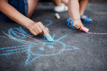 Obraz premium Close up of little girl drawing with chalks on the sidewalk