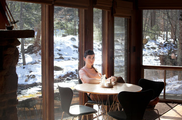 Young woman having beverage at kitchen table 