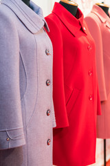 Women's coat in the store. Spring women's coats hanging on a rack in a women's clothing store. vertical photo