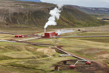 Krafla geothermal power station among mountains on a cloudy summer day. Side building with steam...