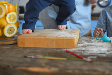 legs of a child standing on the kitchen table.Wooden table sprinkled with flour.Yellow lemons in the background