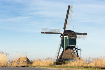 View on an old tradional windmill in the Netherlands, part of historic Dutch culture. The wind makes the blades rotate to provide energy to drain the land so that the land stays dry.