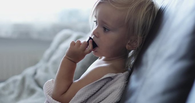 Naked girl sitting on the couch and gnaws a toy.