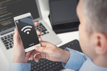 Man using smartphone with wireless symbol