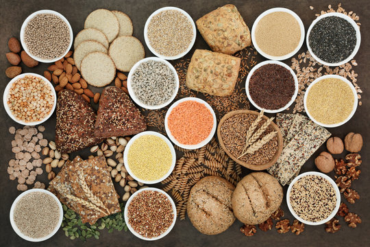 Health food for a high fibre diet with legumes, whole grain bread rolls, whole wheat pasta, seeds, nuts, grain and cereals on lokta paper background. High in antioxidants, vitamins and minerals.