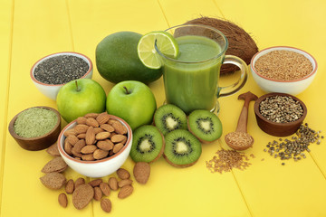 Healthy fruit juice smoothie drink for fitness with matcha powder, almonds, flax, hemp & chia seed, with fresh fruit on yellow wood background. High in omega 3, antioxidants, vitamins & dietary fibre.