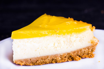 Lemon cheesecake on black background decorated with lemon zest close up